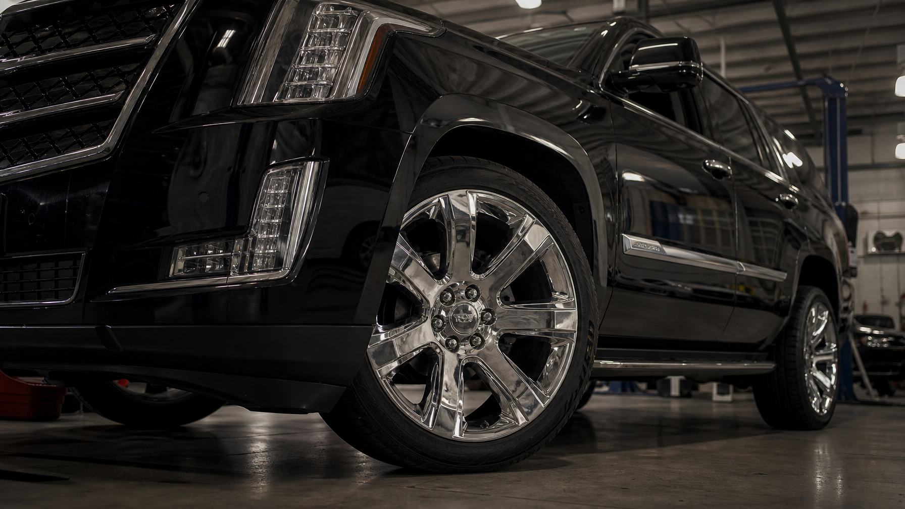 Close-up of a large chrome 24-inch wheel on a full-size SUV at a dealer service bay, illustrating the 2026 GM wheel hub bolt recall