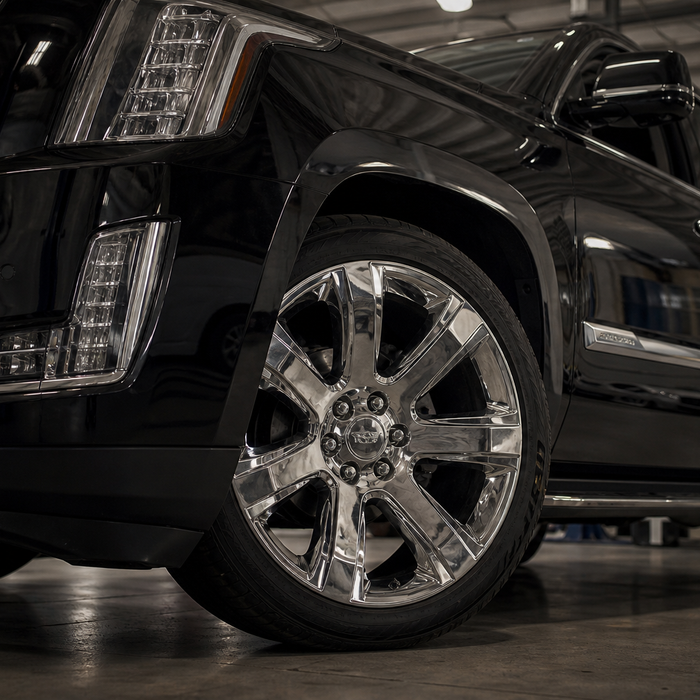 Close-up of a large chrome 24-inch wheel on a full-size SUV at a dealer service bay, illustrating the 2026 GM wheel hub bolt recall