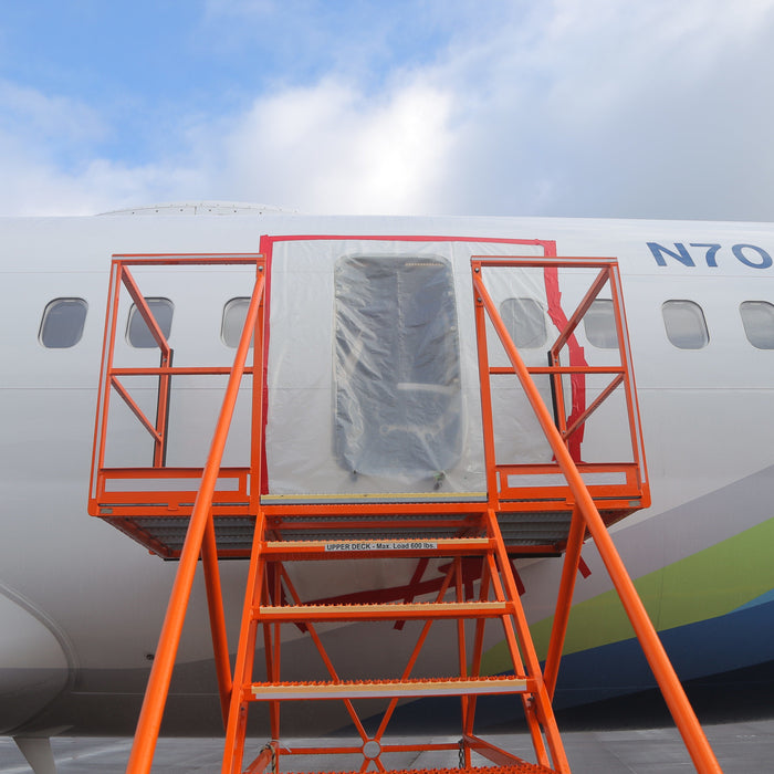 The fuselage of Alaska Airlines Boeing 737-9 N704AL at Portland International Airport, January 7, 2024, showing the plastic-covered opening where the mid-exit door plug separated in flight. Photo: National Transportation Safety Board (public domain).